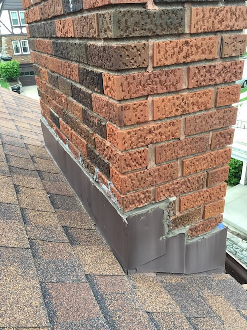 Close-up of a brick chimney with new waterproofing at the base.