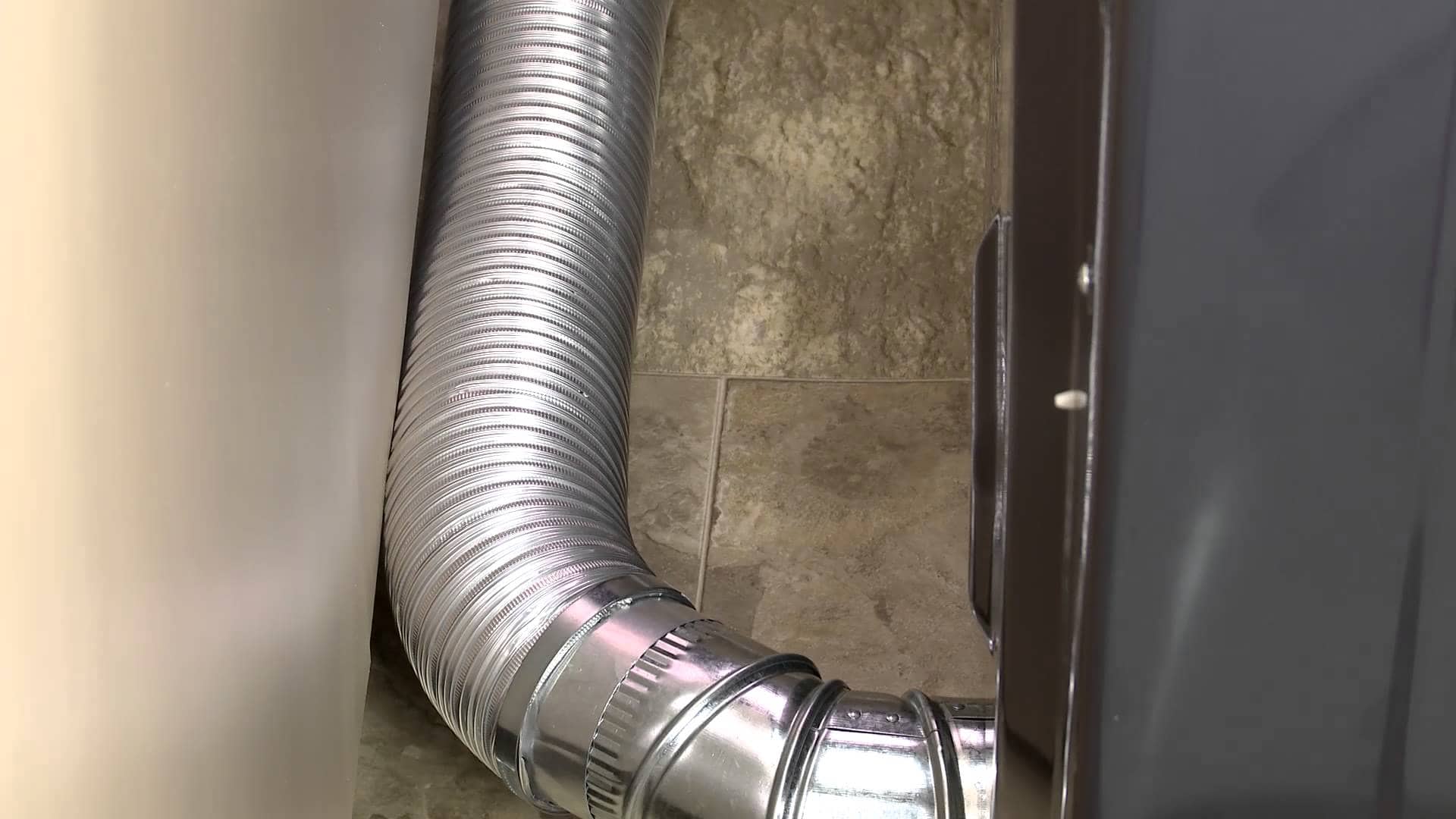 Flexible dryer vent hose connected to the dryer and wall vent.