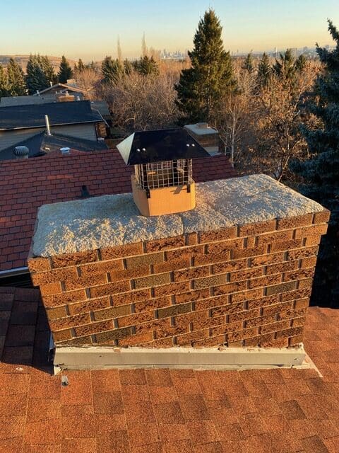 Chimney with new cap installed on brick chimney in residential area.