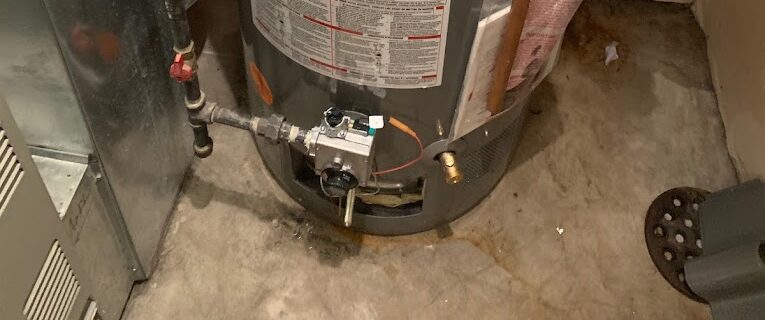 Water heater installation in a basement with plumbing connections and concrete floor.