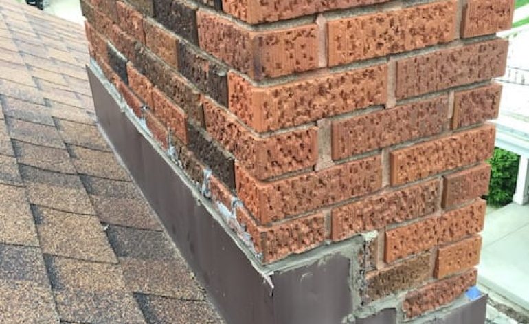 Close-up of a brick chimney with new waterproofing at the base.